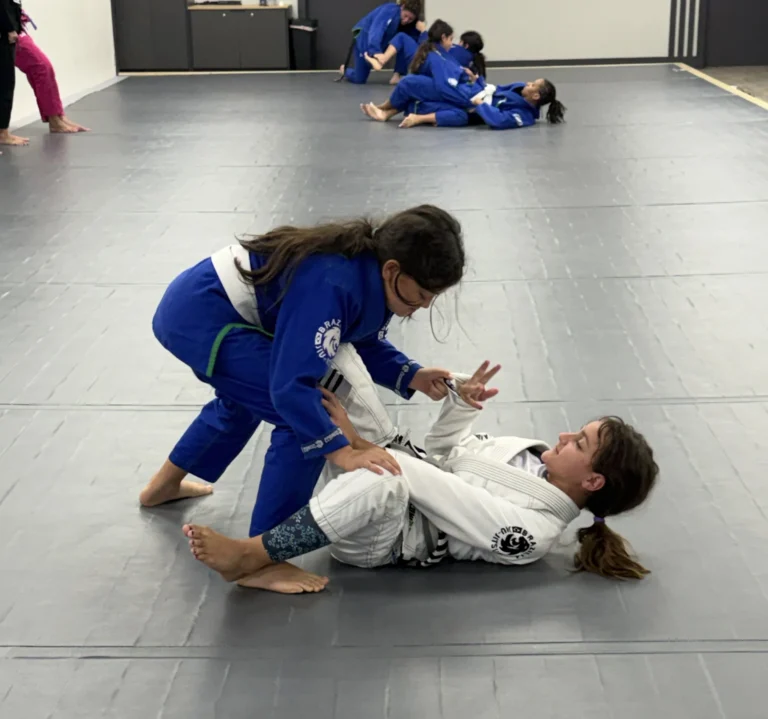 Youth Jiu-Jitsu students developing technique together on the Ceconi academy mats. Young students practicing Brazilian Jiu-Jitsu in blue and white gis